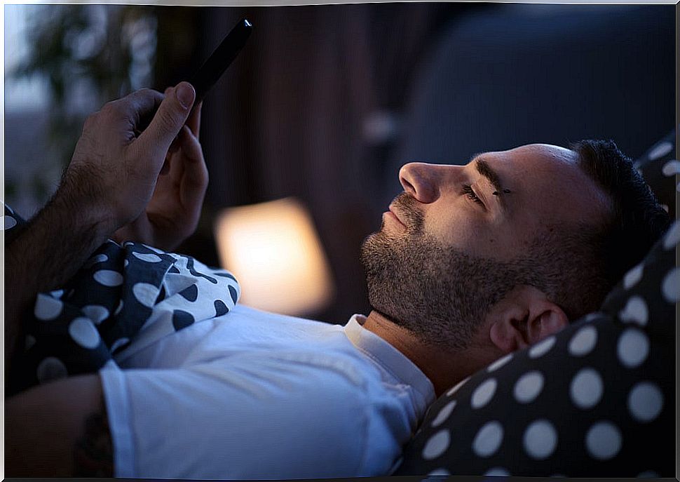 Man looks at mobile in bed because he is not sleepy.