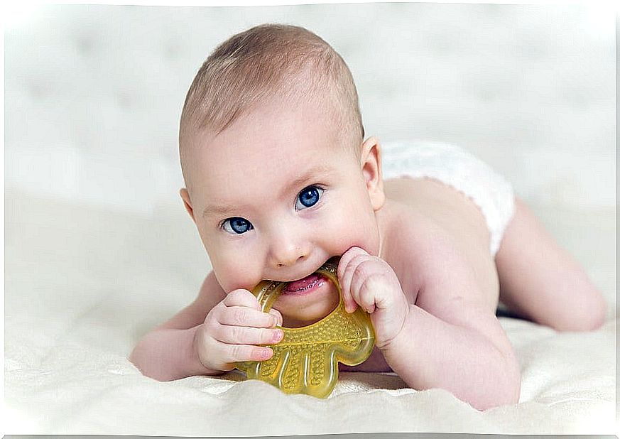 Baby with a teether in his mouth.